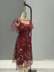 Detailed embroidery on burgundy mesh gown featuring elegant floral vine patterns