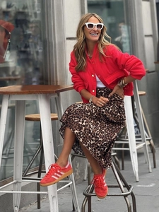 Dettaglio giacca in lana rossa da donna con bottoni dorati e gonna leopardata