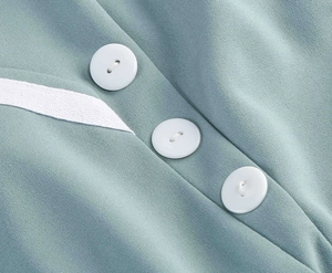 Detail shot of white buttons and drawstring on a light blue polka dot vintage dress