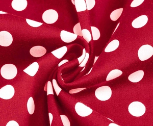 Close-up of soft red cotton fabric with white polka dots showing textile texture