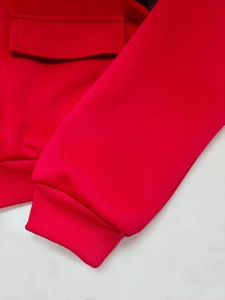 Dettaglio macro della giacca rossa con tasca a patta e polsini elastici a costine morbide