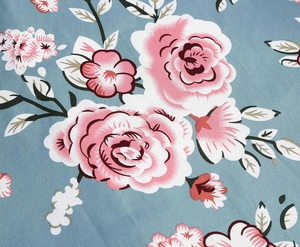 Detailed close-up of blue floral fabric with pink roses and green leaves pattern
