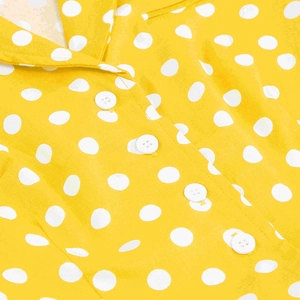 Dettaglio macro dell'abito giallo a pois con bottoni bianchi e trama del tessuto fine