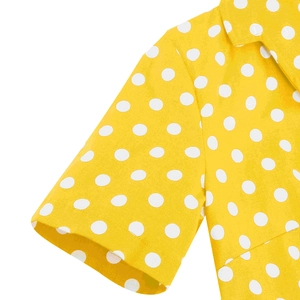 Dettaglio dell'abito giallo a pois bianchi con colletto a revers e cuciture ben rifinite