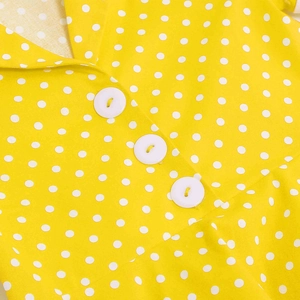 Detail of yellow polka dot girl's dress with white buttons and smooth V-neckline fabric