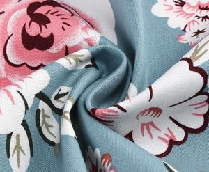 Macro shot of high-quality twill floral fabric with pink blossoms on grey-blue base