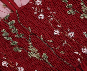 Detail of smocked bodice on a red dress with floral embroidery and mesh fabric