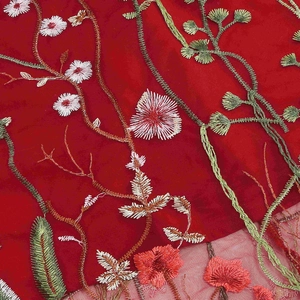 Detailed close-up showing high-density floral embroidery on red mesh fabric of the dress