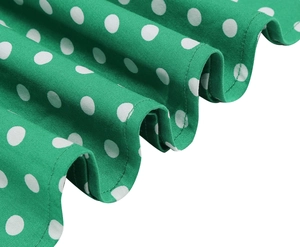 Detail of green Audrey Hepburn style polka dot dress featuring wavy hem and pleated fabric