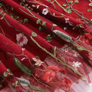 Close-up of red mesh fabric with premium floral embroidery and intricate vine stitching