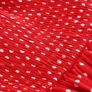 Detailed view of red and white polka dot fabric featuring elastic smocking and ruffle texture