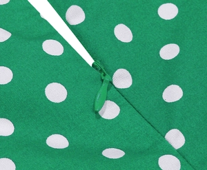Detailed view of the invisible zipper on a green polka dot dress with cotton texture