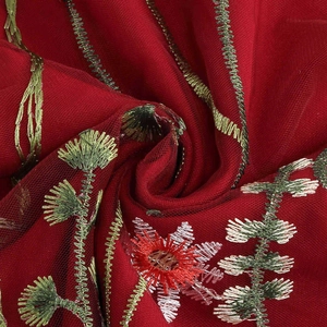 Detailed close-up of intricate floral embroidery on dark red sheer mesh fabric layer