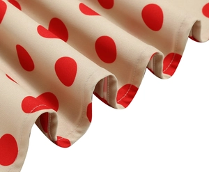Dettaglio del tessuto beige a pois rossi con cuciture bianche sul bordo dell'abito