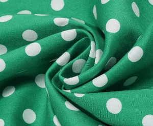 Macro shot of green polka dot fabric texture with fine woven fibers on a vintage dress