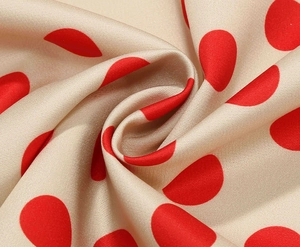 Dettaglio macro di tessuto beige setoso a pois rossi con consistenza morbida