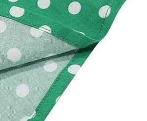 Detailed view of white polka dots on green fabric with clean stitched edge finishing