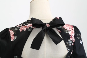 Dettaglio dell'abito floreale nero con un elegante fiocco sulla schiena e maniche a sbuffo