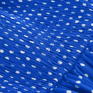 Close-up of royal blue polka dot dress featuring smocked elastic fabric detail