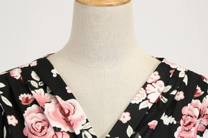 Detailed view of deep V-neckline with pleated details on a black floral rose print dress