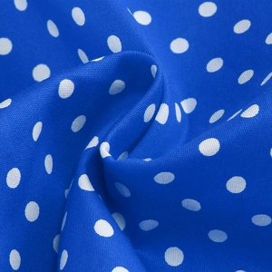 Detailed close-up of royal blue polka dot fabric with smooth texture and soft pleats