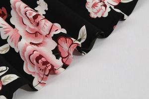 Close-up of floral print on black woven fabric with detailed stitching and wavy hem