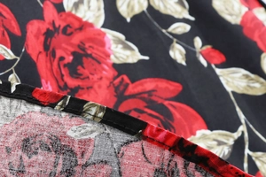 Détail de l'imprimé floral rose rouge sur tissu noir avec couture fine sur le bord du vêtement