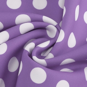 Close-up of purple polka dot fabric with white spots and a silky smooth satin texture