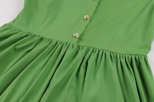 Détail de la robe vintage verte montrant les plis de taille et les boutons bruns
