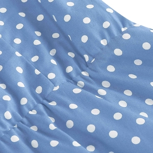 Close-up detail of blue polka dot fabric with smooth texture and soft pleats