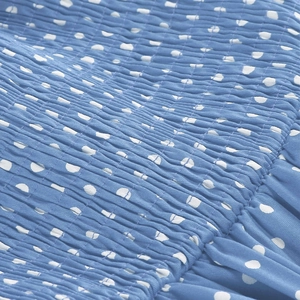 Detailed view of elastic smocked sky blue fabric with white polka dot print texture