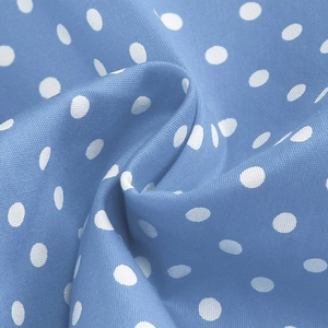 Detailed close-up of light blue polka dot fabric with soft draping and smooth texture