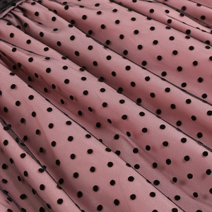 Close-up of pink fabric with black polka dot mesh layers and elegant pleat details