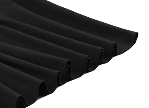 Détail de l'ourlet de la robe noire avec de grands plis ondulés et texture mate