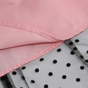 Detail of pink fabric stitching and black mesh with polka dots on retro dress hem