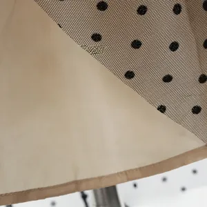 Close-up of black polka dot mesh fabric with smooth beige satin lining texture