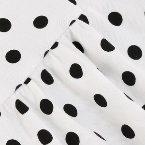 Close-up of white fabric with black polka dots and pleated texture on vintage dress
