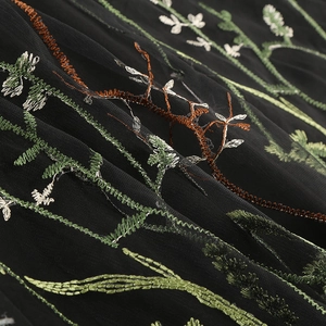 Close-up of black mesh fabric featuring intricate floral embroidery and plant motifs