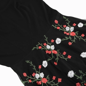 Close-up of intricate red floral embroidery on black mesh fabric of V-neck dress