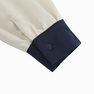 Detailed close-up of the contrasting navy cuff and fabric button on the long sleeve dress