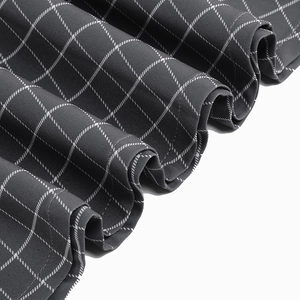 Detail view of dark grey plaid dress showing sharp pleats and white grid pattern texture