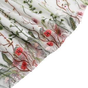 Detailed close-up of premium white mesh fabric with red floral embroidery on elegant dress