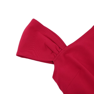 Detailed view of red one-shoulder dress showing pleat craftsmanship and fabric texture