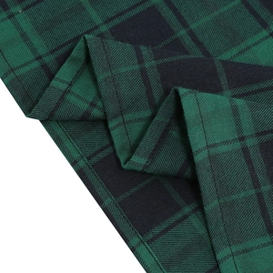 Detailed close-up of green and black plaid fabric texture with precise stitching seams