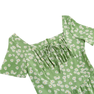 Détail du col carré avec cordon et imprimé marguerites sur une robe verte d'été