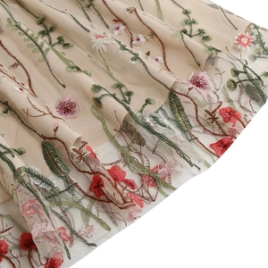 Macro shot of colorful floral embroidery on double-layered mesh fabric dress