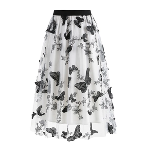 Detail of white mesh skirt featuring intricate black butterfly embroidery and elastic waist