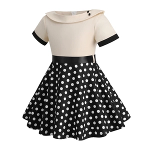 Detail of vintage girls' dress showing ivory bodice, black belt, and polka dot skirt