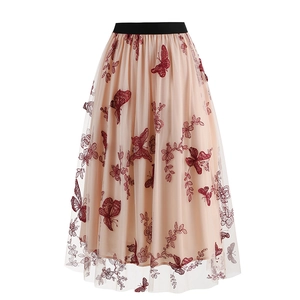 Detailed close-up of intricate red butterfly embroidery on beige tulle mesh skirt