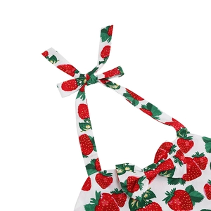 Detail of girls floral dress featuring strawberry print and halter neck with a bow tie